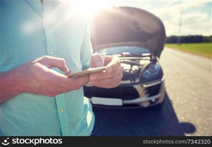 road trip, transport, travel, technology and people concept - close up of man with smartphone and broken car. close up of man with smartphone and broken car
