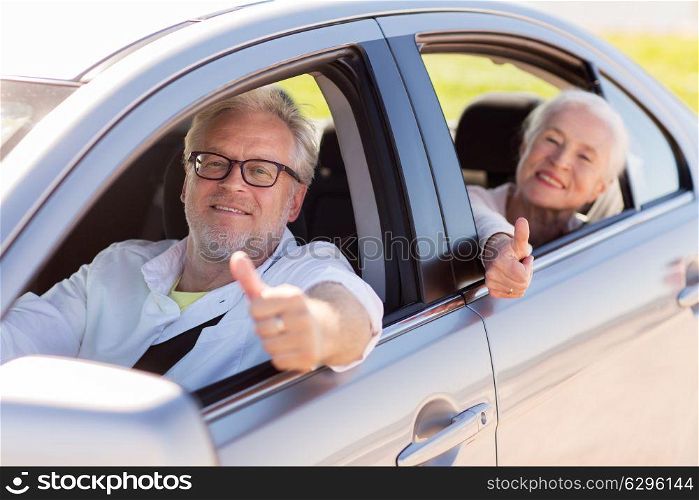 road trip, travel and old people concept - happy senior couple driving in car and showing thumbs up. senior couple driving in car and showing thumbs up