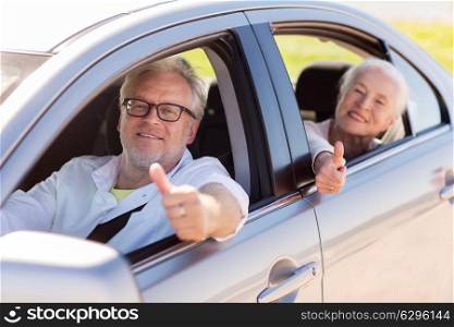 road trip, travel and old people concept - happy senior couple driving in car and showing thumbs up. senior couple driving in car and showing thumbs up