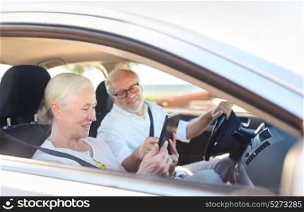 road trip, travel and old people concept - happy senior couple with tablet pc computer driving in car. happy senior couple with tablet pc driving in car