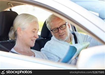road trip, travel and old people concept - happy senior couple with map driving in car. happy senior couple with map driving in car