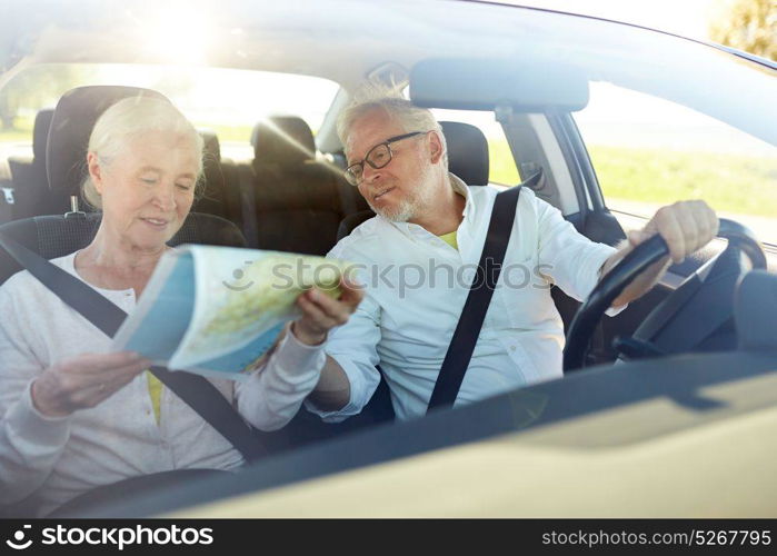 road trip, travel and old people concept - happy senior couple with map driving in car. happy senior couple with map driving in car