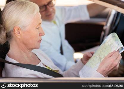 road trip, travel and old people concept - happy senior couple with map driving in car. happy senior couple with map driving in car