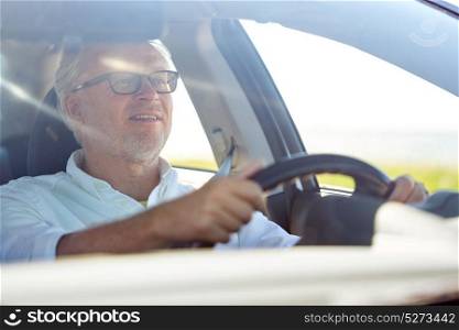 road trip, travel and old people concept - happy senior man in glasses driving car. happy senior man in glasses driving car
