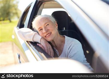 road trip, travel and old people concept - happy senior woman driving in car with open window. happy senior woman driving in car with open window