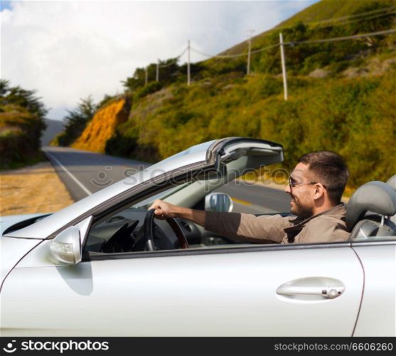 road trip, travel and people concept - happy man driving convertible car over road and big sur hills background in california. man driving convertible car over big sur hills