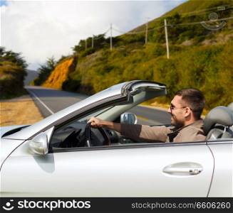 road trip, travel and people concept - happy man driving convertible car over road and big sur hills background in california. man driving convertible car over big sur hills