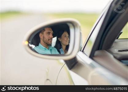road trip, travel and people concept - side mirror reflection of happy couple driving car