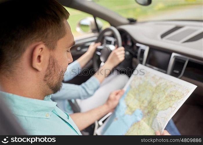 road trip, travel, destination and people concept - happy man and woman driving in car and searching location on map