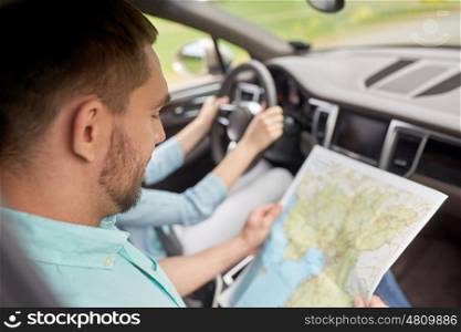 road trip, travel, destination and people concept - happy man and woman driving in car and searching location on map