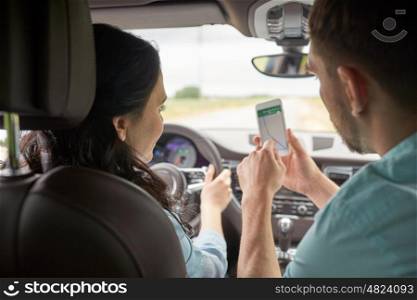road trip, travel, destination technology and people concept - happy man and woman with navigator on smartphone driving in car