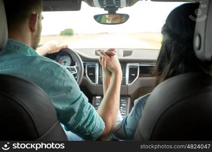 road trip, travel, love and people concept - happy couple driving in car and holding hands
