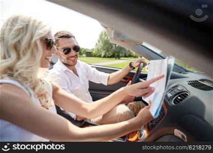 road trip, travel, summer vacation and people concept - happy man and woman driving in cabriolet car with map