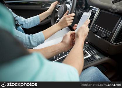road trip, travel, technology and people concept - happy man and woman with smartphone driving in car
