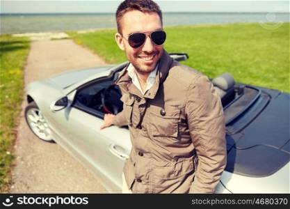 road trip, travel, transport, leisure and people concept - happy man near cabriolet car outdoors