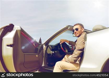 road trip, travel, transport, leisure and people concept - happy man opening door of cabriolet car outdoors