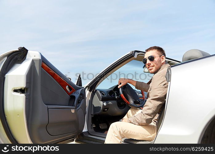 road trip, travel, transport, leisure and people concept - happy man opening door of cabriolet car outdoors