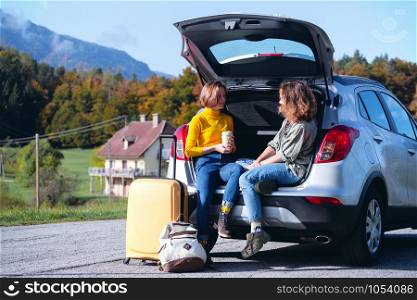 road trip - Two teenager smiling girls sitting in the boot