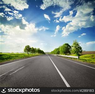 Road with a dividing strip under a blue cloudy sky