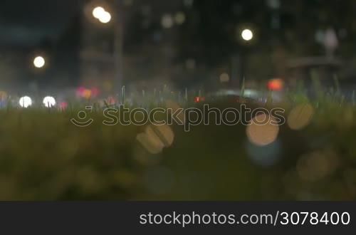 Road with traffic at night and close-up of glass orb on roadside green grass in foreground