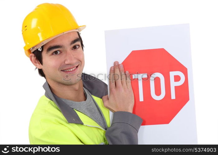 road worker hiding the letter s of a stop sign