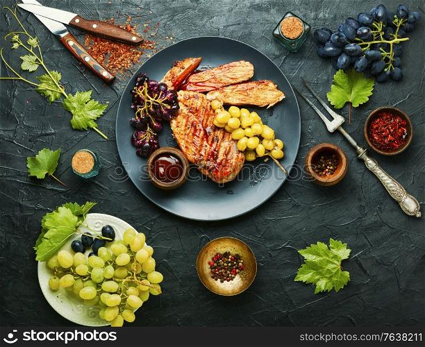 Roast chicken breast with grapes.Summer BBQ.Barbecued chicken meat.. Grilled chicken breast on concrete background