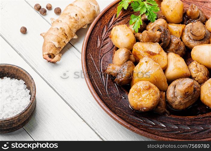 Roast Jerusalem artichoke with champignon mushrooms.Roast with potatoes and mushrooms.Vegetarian food.. Roast Jerusalem artichoke