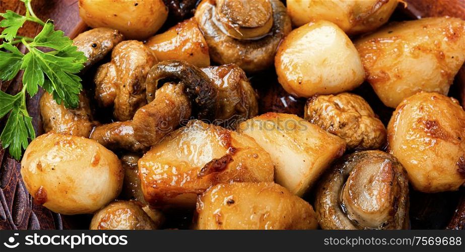 Roast Jerusalem artichoke with champignon mushrooms.Roast with potatoes and mushrooms.Vegetarian food.Food background. Baked Jerusalem artichoke