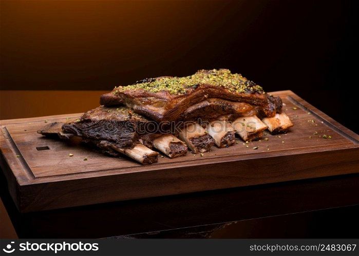 roast meat with bone on a wooden tray, dark background, isolated. dish on black background