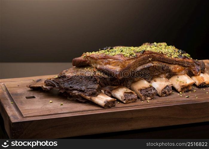roast meat with bone on a wooden tray, dark background, isolated. dish on black background
