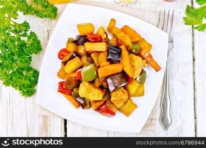 Roast meat, zucchini, eggplant, carrot and sweet pepper with honey, soy sauce and red wine in a plate on a napkin against the background of the wooden planks on top