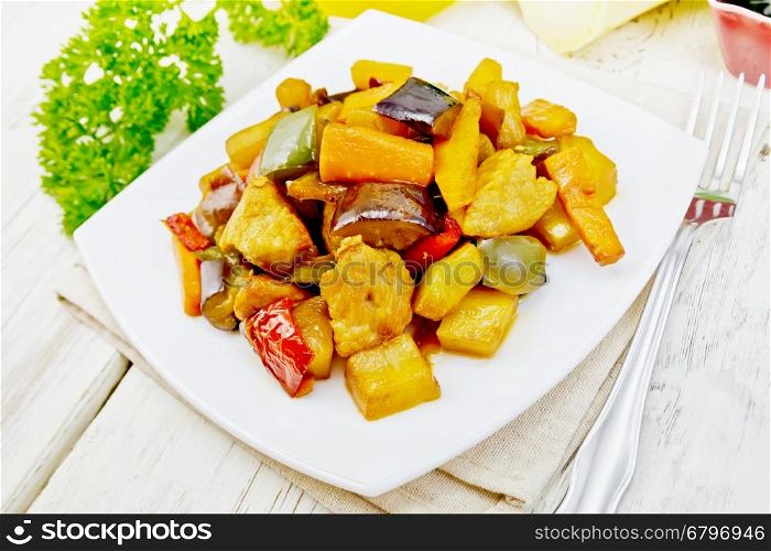 Roast meat, zucchini, eggplant, carrot and sweet pepper with honey, soy sauce and red wine in a white plate on a napkin against the background of wooden boards
