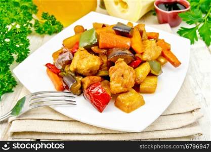Roast meat, zucchini, eggplant, carrot and sweet pepper with honey, soy sauce and red wine in a plate on a napkin against the background of wooden boards