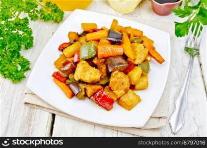Roast meat, zucchini, eggplant, carrot and sweet pepper with honey, soy sauce and red wine in a plate on a napkin on the background light wooden boards