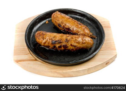 Roast sausages at pan with sauce on a white background