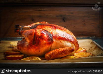 Roast whole turkey or chicken over wooden background, side view