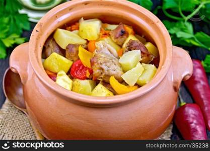Roast with chicken, potatoes, squash and sweet peppers in a clay pot on a napkin of burlap, spoon, parsley on a wooden boards background