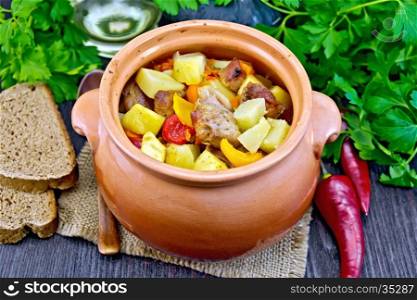 Roast with chicken, potatoes, squash and sweet peppers in a clay pot on a napkin of burlap, bread and parsley on a wooden board background
