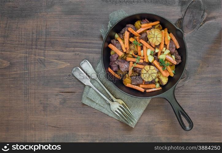 Roast with vegetables in a cast iron skillet on a wooden table