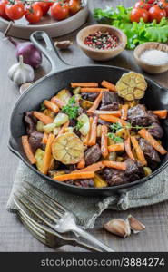 Roast with vegetables in a cast iron skillet on a wooden table