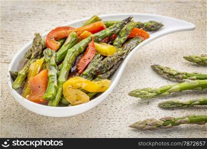 roasted asparagus salad on a teardrop shaped bowl against white painted rustic wood with fresh asparagus