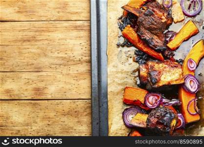 Roasted beef ribs with pumpkin.Piece of baked beef ribs.Copy space. Grilled meat with autumn pumpkin