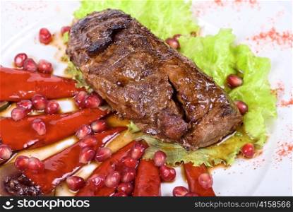 Roasted beef steak with pomegranate closeup at plate