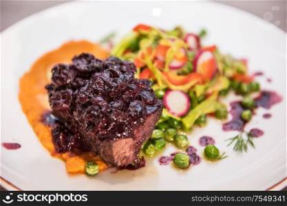 Roasted beef with berries sauce garnished with vegetables. Roasted beef with berries sauce