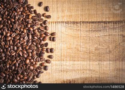 Roasted brown coffee beans spilled on wooden table background. Tabletop view. Roasted brown coffee beans spilled on wooden table background.