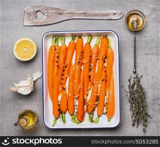 Roasted carrots with green herbs, garlic ,lemon and honey on gray concrete background, top view, flat lay. Healthy , clean food or vegetarian cooking and eating concept