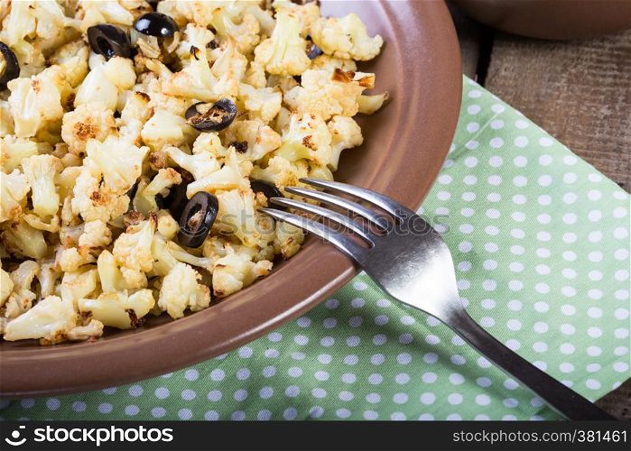 roasted cauliflower with olives on a wooden table