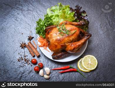 Roasted chicken / baked whole chicken grilled on plate with herbs and spices and dark background on top view