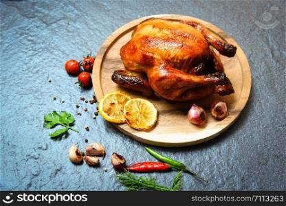 Roasted chicken / baked whole chicken grilled with herbs and spices on wooden plate and dark background