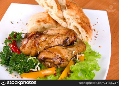 roasted chicken drumstick garnished with fresh green salad, pepper and greens